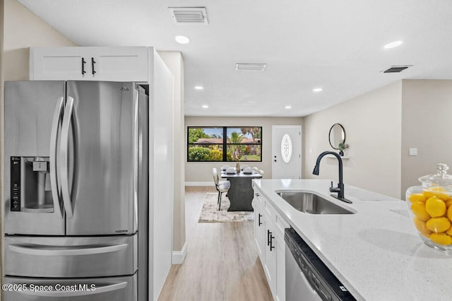 532 Buckingham Ave, Melbourne, FL 32935 - kitchen with stainless steel appliances, light stone countertops, light wood-style flooring, white cabinets, and recessed lighting