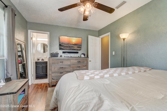 1032 Bernice Rd, Rockledge, FL 32955 - bedroom with a textured wall, wood finished floors, ensuite bathroom, a ceiling fan, and a textured ceiling