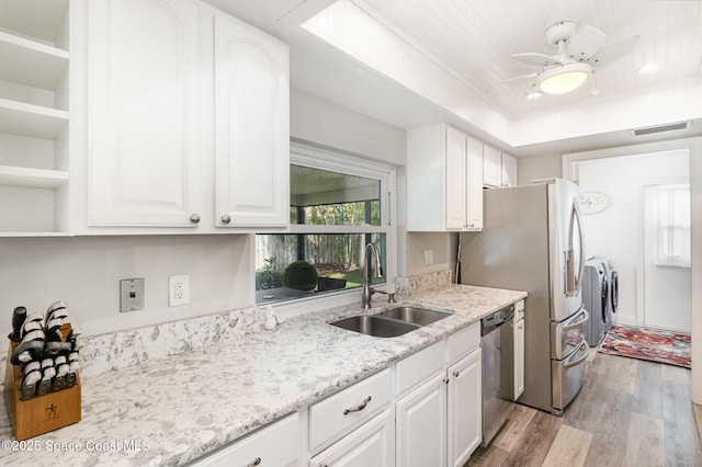 658 Hibiscus Dr, Satellite Beach, FL 32937 - kitchen with stainless steel appliances, washing machine and dryer, light wood-type flooring, and white cabinetry