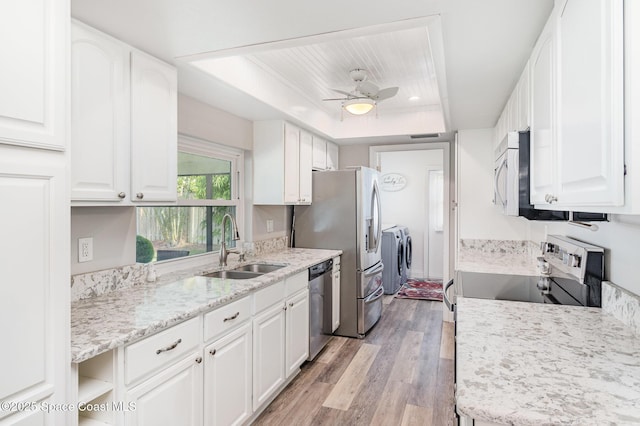 658 Hibiscus Dr, Satellite Beach, FL 32937 - kitchen with separate washer and dryer, appliances with stainless steel finishes, light wood-style floors, white cabinets, and a ceiling fan