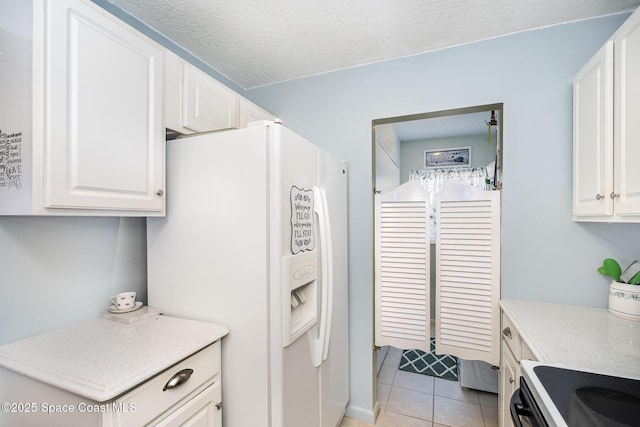 1005 Knox Mcrae Dr Unit B-210, Titusville, FL 32780 - kitchen featuring white fridge with ice dispenser, light tile patterned floors, white cabinets, and a textured ceiling