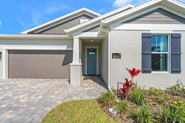 9374 Corvo Ct, Melbourne, FL 32940 - view of front of property with an attached garage, board and batten siding, decorative driveway, and stucco siding