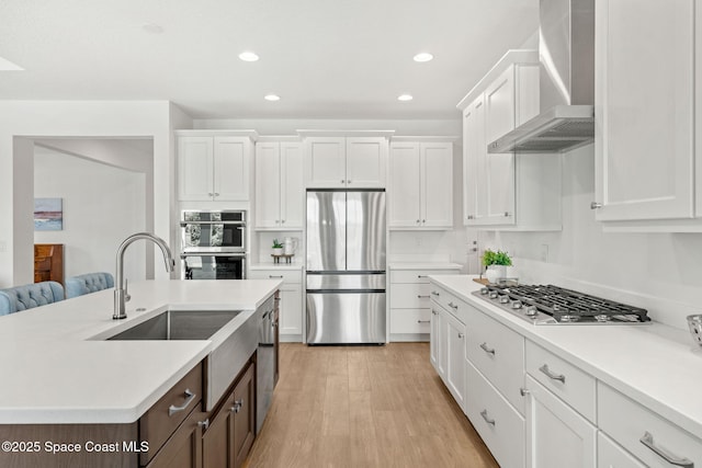 9374 Corvo Ct, Melbourne, FL 32940 - kitchen featuring appliances with stainless steel finishes, wall chimney exhaust hood, white cabinetry, dark brown cabinetry, and light countertops
