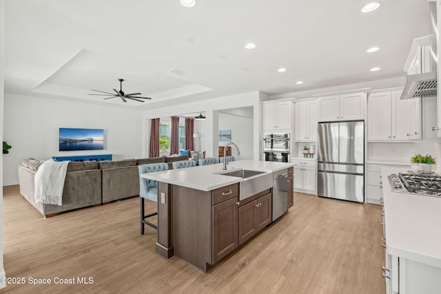 9374 Corvo Ct, Melbourne, FL 32940 - kitchen with stainless steel appliances, light countertops, white cabinetry, light wood finished floors, and a raised ceiling