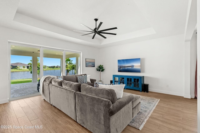 9374 Corvo Ct, Melbourne, FL 32940 - living room with a tray ceiling, ceiling fan, and light wood-type flooring