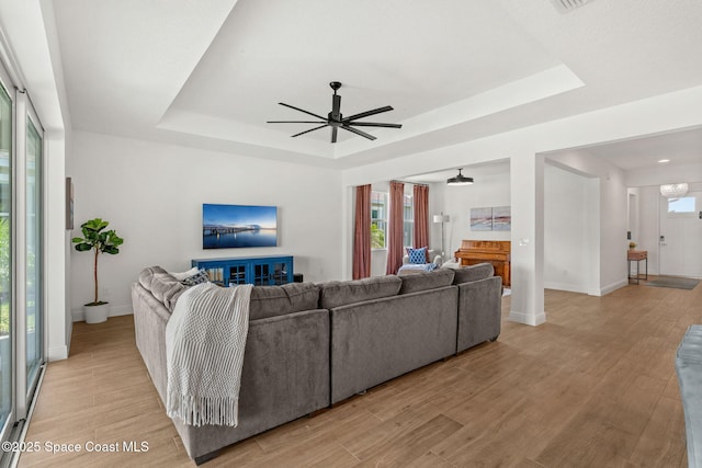 9374 Corvo Ct, Melbourne, FL 32940 - living room with a tray ceiling, a ceiling fan, and light wood finished floors