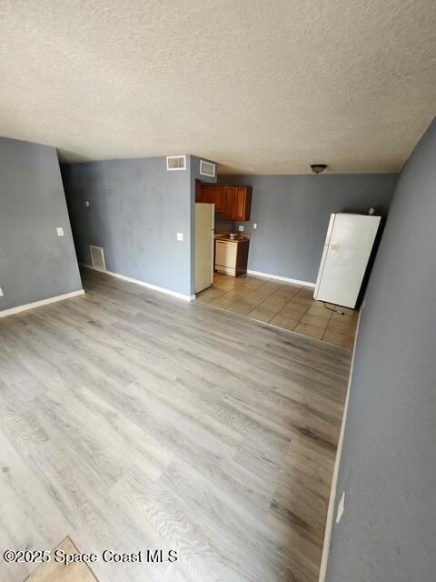 2101 Forest Knoll Dr NE Unit 01-101, Palm Bay, FL 32905 - unfurnished living room with a textured ceiling and light wood-style flooring