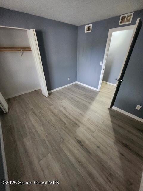 2101 Forest Knoll Dr NE Unit 01-101, Palm Bay, FL 32905 - unfurnished bedroom featuring wood finished floors, a textured ceiling, and a closet