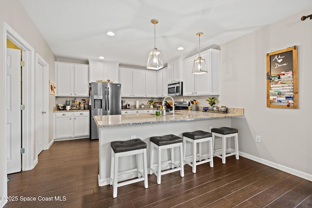 739 Fiddleleaf Cir, Melbourne, FL 32904 - kitchen with stainless steel appliances, a peninsula, recessed lighting, dark wood finished floors, and white cabinets