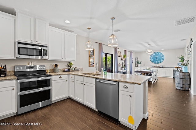 739 Fiddleleaf Cir, Melbourne, FL 32904 - kitchen with appliances with stainless steel finishes, a peninsula, dark wood-style floors, white cabinetry, and recessed lighting