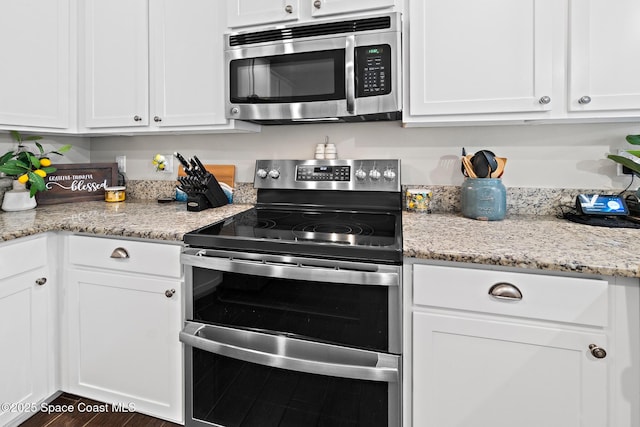 739 Fiddleleaf Cir, Melbourne, FL 32904 - kitchen with stainless steel appliances, white cabinets, light stone counters, and wood finished floors