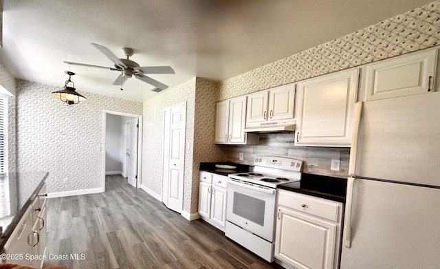 658 Ervin St, Sebastian, FL 32958 - kitchen with white appliances, under cabinet range hood, wallpapered walls, ceiling fan, and dark countertops