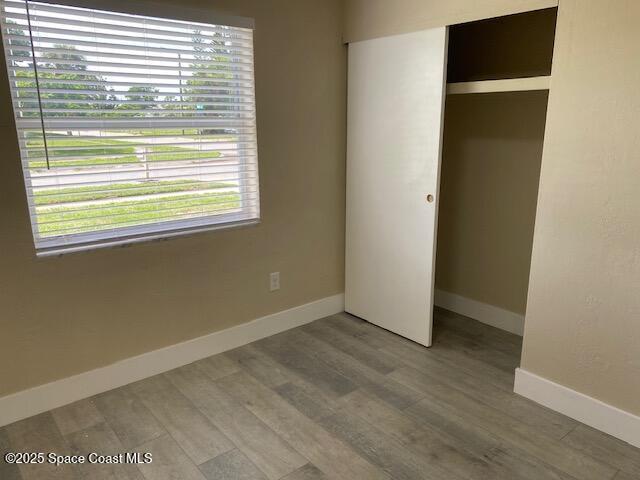 3037 Rowe St NE, Palm Bay, FL 32905 - unfurnished bedroom with multiple windows, a closet, and wood finished floors