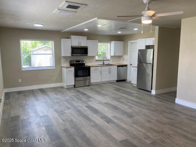 3037 Rowe St NE, Palm Bay, FL 32905 - kitchen with stainless steel appliances, white cabinetry, light wood finished floors, and recessed lighting