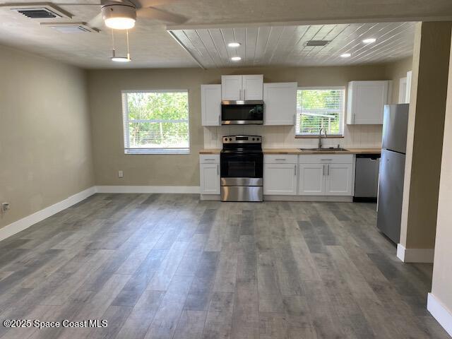 3037 Rowe St NE, Palm Bay, FL 32905 - kitchen with appliances with stainless steel finishes, a ceiling fan, white cabinetry, wood finished floors, and recessed lighting
