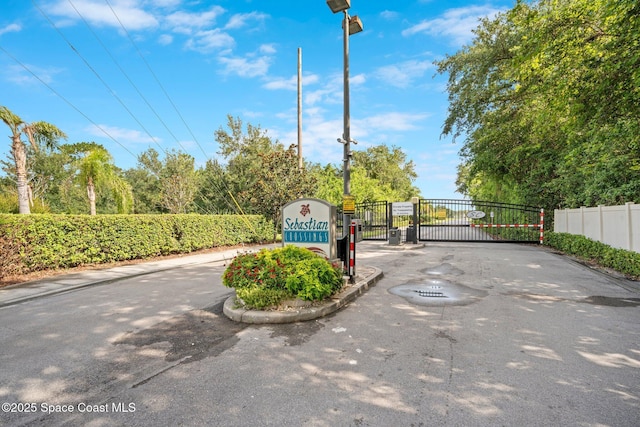 103 Amherst Ln, Sebastian, FL 32958 - view of asphalt street featuring a gate, curbs, street lighting, and a gated entry