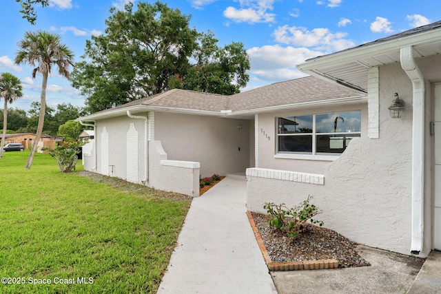 1119 Manatee Dr, Rockledge, FL 32955 - view of exterior entry with a yard, stucco siding, and a shingled roof