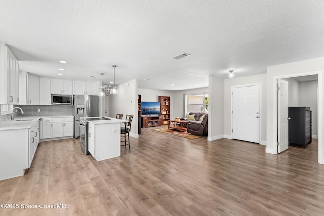 1119 Manatee Dr, Rockledge, FL 32955 - kitchen featuring stainless steel appliances, open floor plan, a kitchen island, a breakfast bar, and light wood finished floors