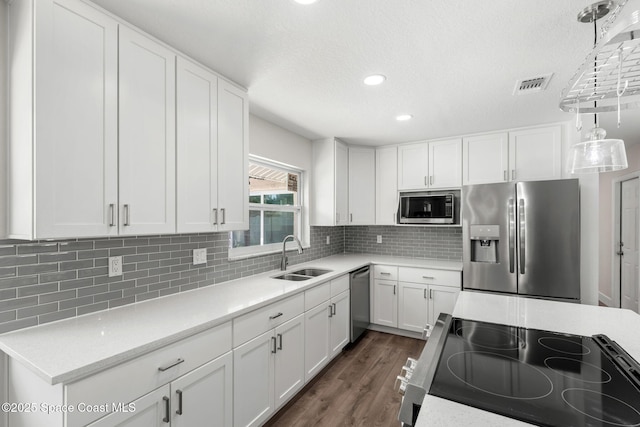 1119 Manatee Dr, Rockledge, FL 32955 - kitchen with appliances with stainless steel finishes, white cabinets, decorative backsplash, dark wood-type flooring, and recessed lighting