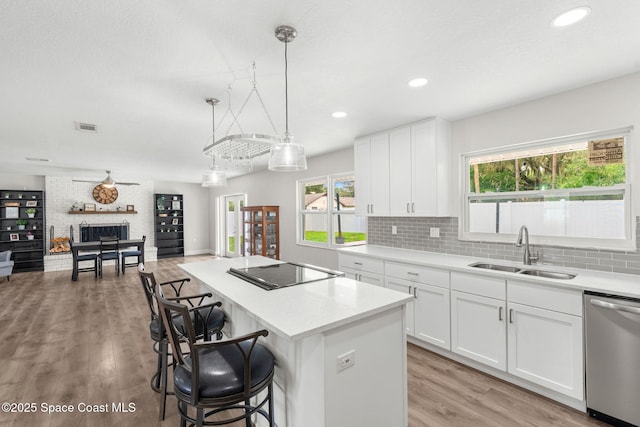 1119 Manatee Dr, Rockledge, FL 32955 - kitchen featuring dishwasher, black electric cooktop, a kitchen island, a breakfast bar, and tasteful backsplash