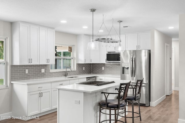 1119 Manatee Dr, Rockledge, FL 32955 - kitchen with stainless steel appliances, white cabinetry, decorative backsplash, light wood finished floors, and recessed lighting