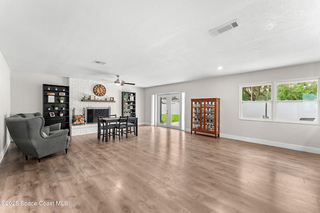 1119 Manatee Dr, Rockledge, FL 32955 - living room with a textured ceiling, a fireplace, ceiling fan, and wood finished floors
