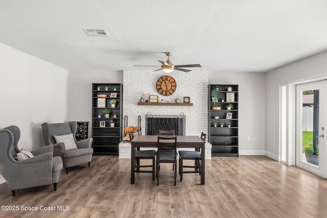 1119 Manatee Dr, Rockledge, FL 32955 - dining space with a fireplace, light wood-style flooring, a ceiling fan, and a textured ceiling