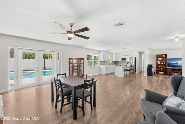 1119 Manatee Dr, Rockledge, FL 32955 - dining area with french doors, light wood-type flooring, ceiling fan, and a textured ceiling