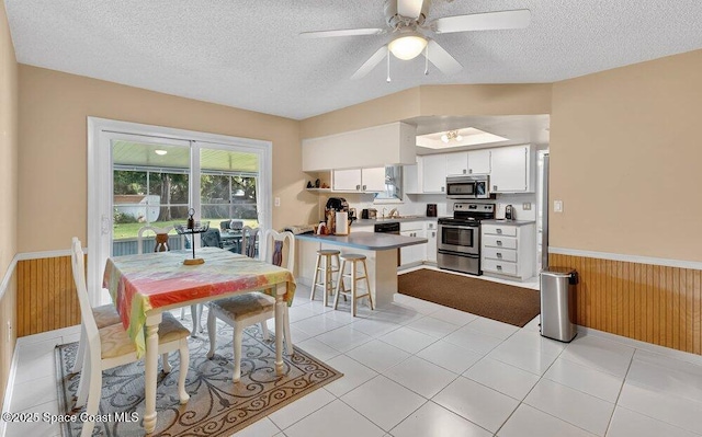 631 Dundee Cir, Melbourne, FL 32904 - dining area featuring a textured ceiling, a wainscoted wall, a ceiling fan, wooden walls, and light tile patterned floors