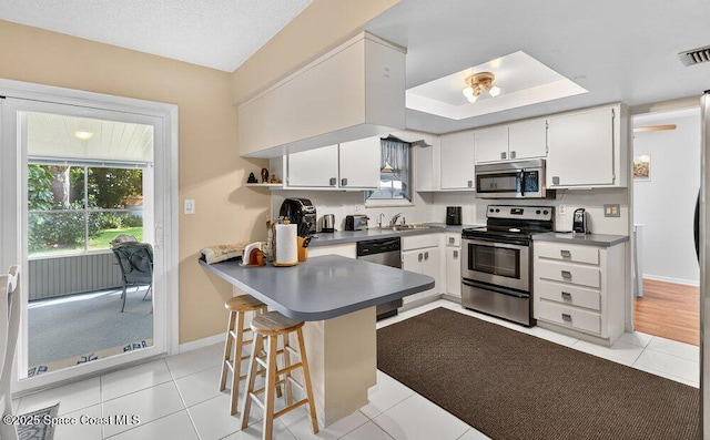 631 Dundee Cir, Melbourne, FL 32904 - kitchen with stainless steel appliances, open shelves, a peninsula, light tile patterned floors, and a kitchen bar