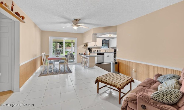 631 Dundee Cir, Melbourne, FL 32904 - living room featuring a wainscoted wall, a ceiling fan, a textured ceiling, light tile patterned floors, and wood walls