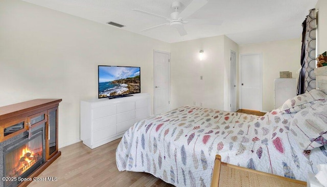 631 Dundee Cir, Melbourne, FL 32904 - bedroom with wood finished floors, a glass covered fireplace, and a ceiling fan