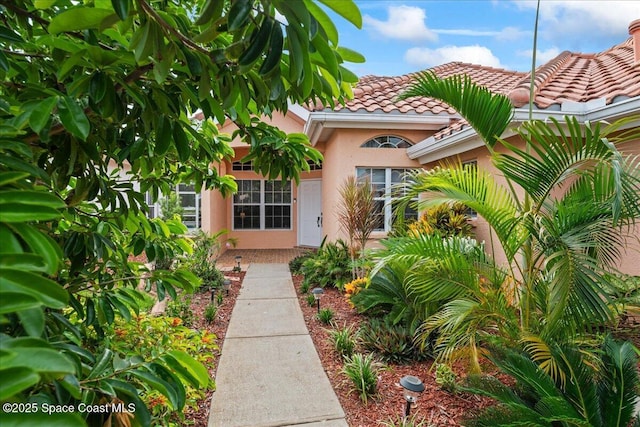 442 Carmel Dr, Melbourne, FL 32940 - view of exterior entry with stucco siding and a tiled roof