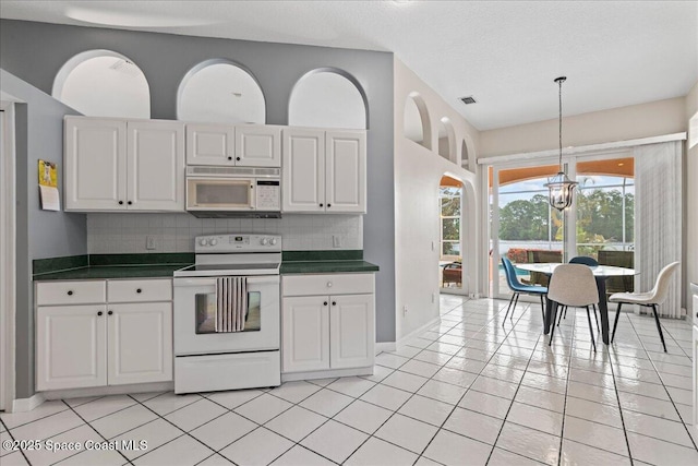 442 Carmel Dr, Melbourne, FL 32940 - kitchen featuring white appliances, dark countertops, decorative backsplash, and a chandelier