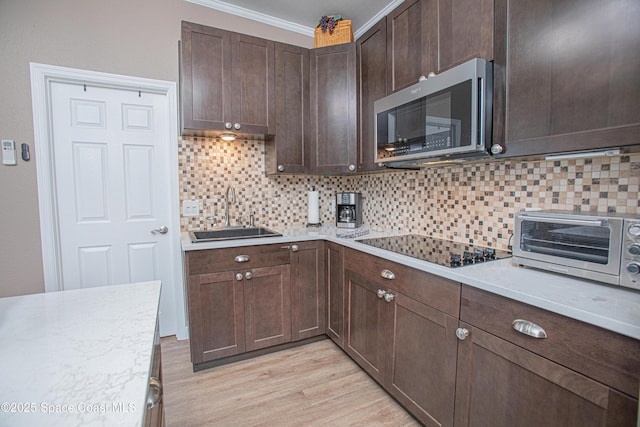 110 Windsong Way, Titusville, FL 32780 - kitchen with stainless steel microwave, black electric cooktop, light countertops, light wood-style flooring, and decorative backsplash