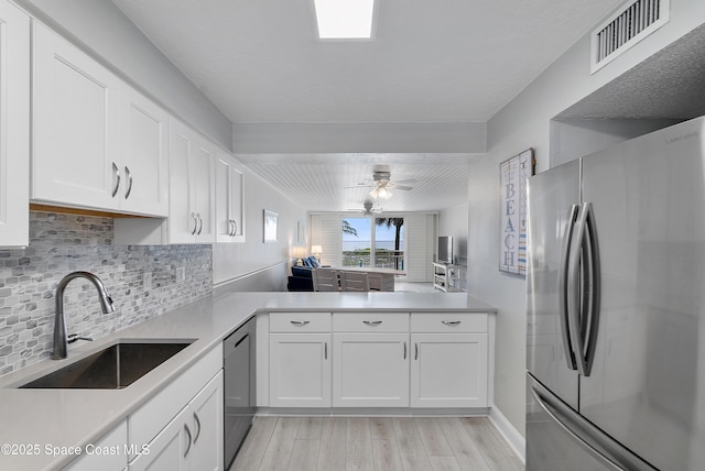 2101 S Atlantic Ave Unit 205, Cocoa Beach, FL 32931 - kitchen with appliances with stainless steel finishes, light wood-style flooring, decorative backsplash, white cabinets, and light countertops