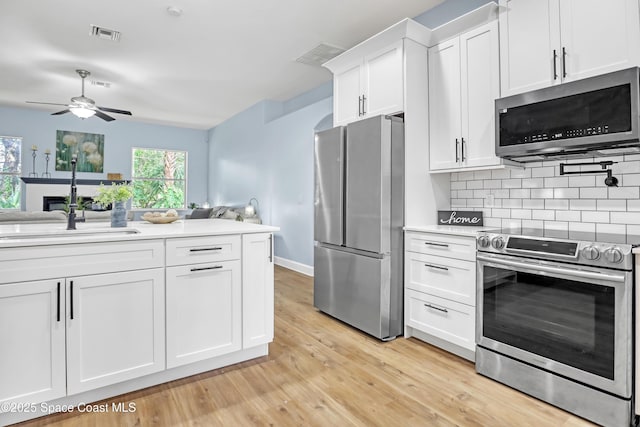2559 Christopher Dr, Titusville, FL 32780 - kitchen with stainless steel appliances, light countertops, ceiling fan, backsplash, and white cabinetry