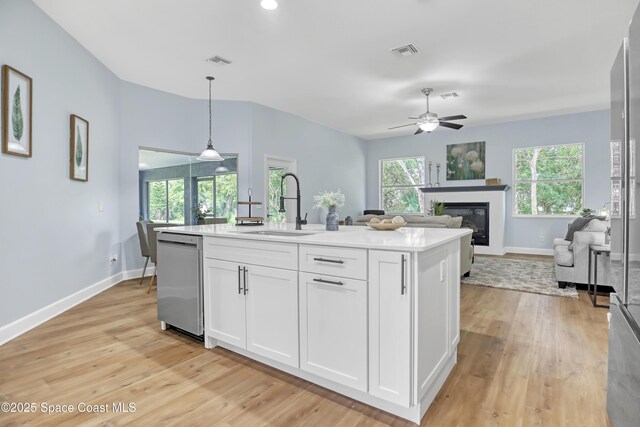 2559 Christopher Dr, Titusville, FL 32780 - kitchen with stainless steel dishwasher, a glass covered fireplace, light wood-style flooring, and white cabinetry