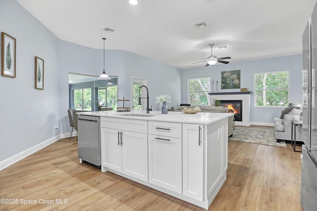 2559 Christopher Dr, Titusville, FL 32780 - kitchen featuring stainless steel dishwasher, a glass covered fireplace, white cabinetry, light wood finished floors, and light countertops