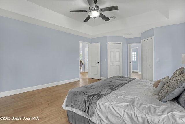 2559 Christopher Dr, Titusville, FL 32780 - bedroom with a raised ceiling, light wood-style floors, multiple closets, and ceiling fan