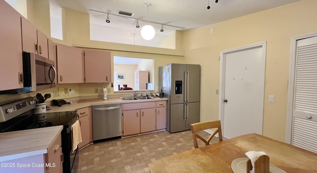 1469 California Dr, Melbourne, FL 32940 - kitchen featuring appliances with stainless steel finishes, light countertops, rail lighting, hanging light fixtures, and a textured ceiling