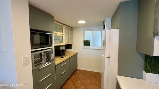 650 N Atlantic Ave Unit 406, Cocoa Beach, FL 32931 - kitchen featuring freestanding refrigerator, light countertops, glass insert cabinets, and dark tile patterned floors