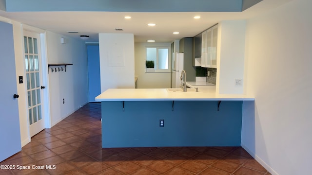 650 N Atlantic Ave Unit 406, Cocoa Beach, FL 32931 - kitchen with a breakfast bar area, a peninsula, light countertops, recessed lighting, and decorative backsplash