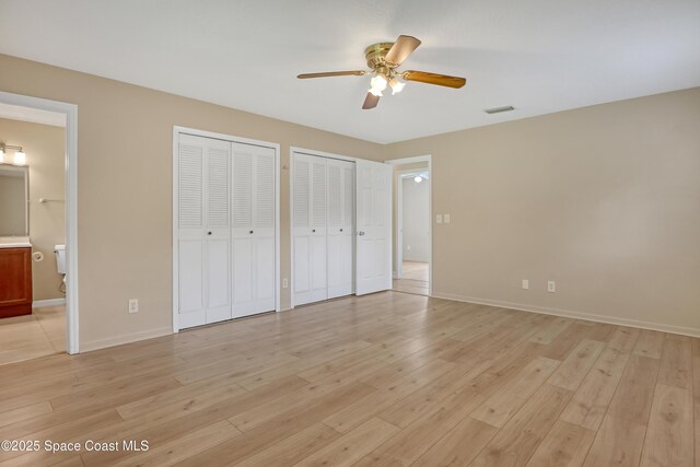 4480 Westview Ln, Titusville, FL 32780 - unfurnished bedroom featuring two closets, light wood-type flooring, connected bathroom, and ceiling fan