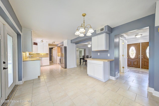 949 Brunswick Ln, Rockledge, FL 32955 - kitchen featuring a chandelier, white cabinets, freestanding refrigerator, and light countertops