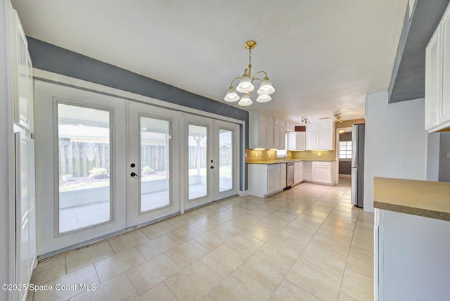 949 Brunswick Ln, Rockledge, FL 32955 - kitchen with french doors, a chandelier, stainless steel appliances, white cabinets, and light tile patterned flooring