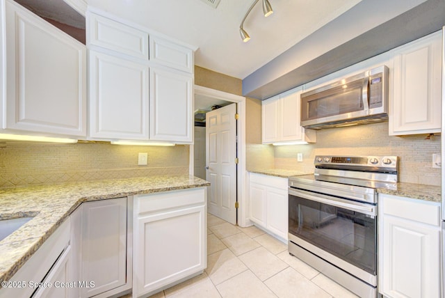 949 Brunswick Ln, Rockledge, FL 32955 - kitchen featuring appliances with stainless steel finishes, white cabinetry, light tile patterned flooring, decorative backsplash, and light stone countertops