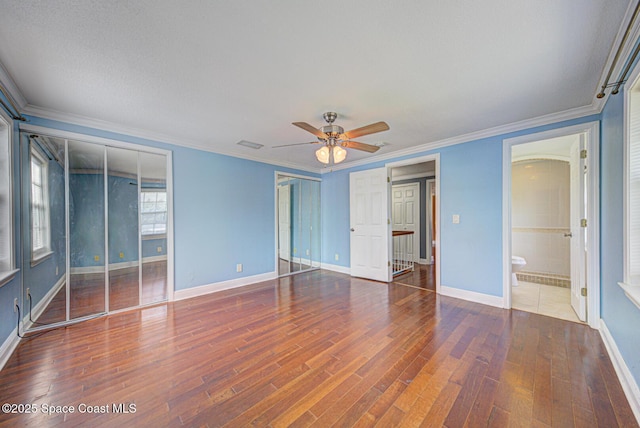949 Brunswick Ln, Rockledge, FL 32955 - unfurnished bedroom with two closets, wood finished floors, crown molding, and ceiling fan