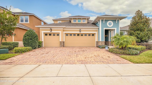 2683 Amati Dr, Kissimmee, FL 34741 - view of front facade featuring decorative driveway, an attached garage, stone siding, and stucco siding