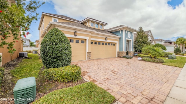 2683 Amati Dr, Kissimmee, FL 34741 - view of front of home with decorative driveway, a garage, stucco siding, stone siding, and a front lawn